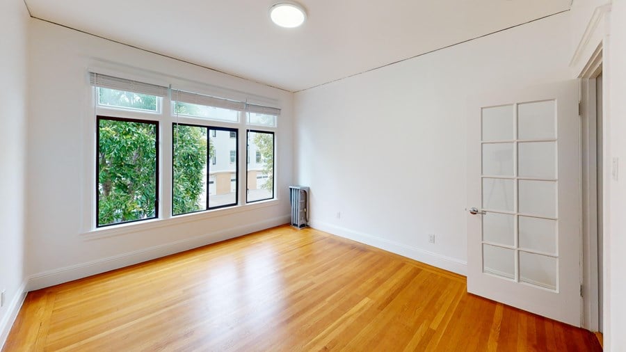 A room with a white wall and a wooden floor.
